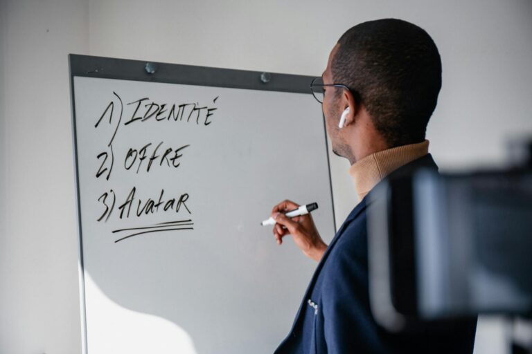 Businessman writing on a whiteboard during a modern office meeting.